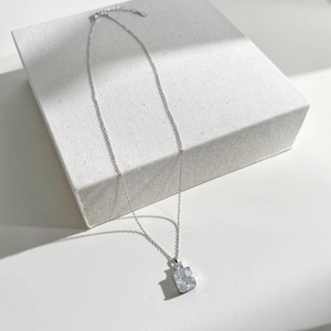 Macro shot of S925 sterling silver necklace with rectangle cut zircon on white pedestal
