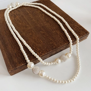 Detail of double-layer pearl necklace with sparkling rhinestone spheres on wood base