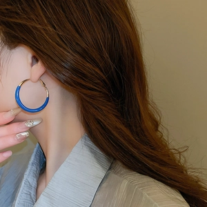 Close-up of royal blue and gold hoop earrings worn with elegant urban style