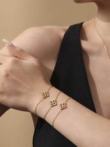 Nahaufnahme von drei goldenen Kleeblatt-Armbändern mit Zirkonia am Handgelenk eines Models