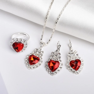 Silver jewelry set with red heart gems and crystal rhinestones on white fabric
