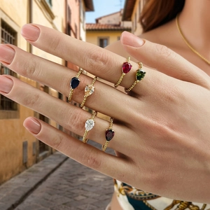 Stackable gold beaded rings with pear-cut colorful zircon gemstones on woman's hand