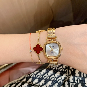 Elegant gold square quartz watch with metal mesh strap and clover bracelet on wrist