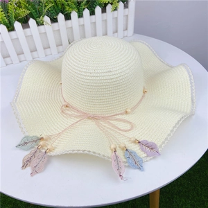 Beige wide brim straw sun hat with wavy edges and colorful embroidered leaf charms