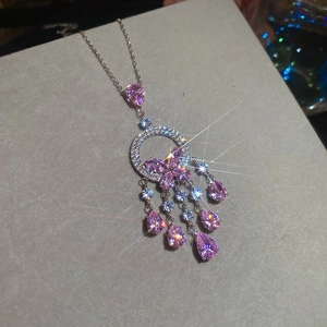 Close-up of a silver dreamcatcher necklace with pink teardrop stones and tassels
