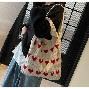 Bolso de hombro de punto con diseño de corazón rojo y textura, llevado por modelo