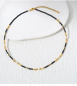 Detail of beaded necklace featuring black spinel beads, gold cubes and pearl accents