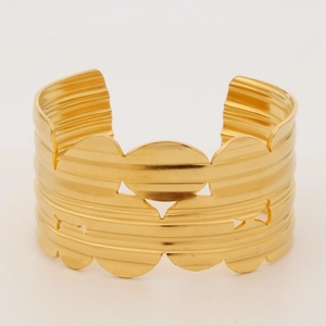 Detail of wide gold stainless steel bangle featuring hammered texture and circular cutouts