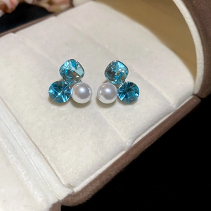 Detailed macro view of 18k gold plated square blue zircon and white pearl stud earrings