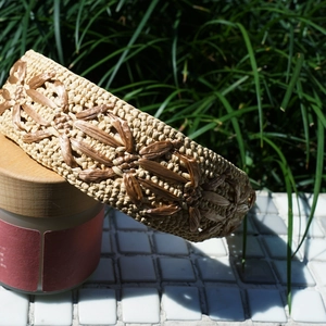 Detailed texture of woven raffia headband in beige and brown on white tile surface