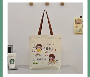 Detail of canvas tote bag showing cute cartoon girl illustration and sturdy brown handles