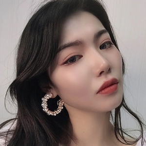 Baroque C-shaped gold hoop earrings with white pearls and rhinestones on a female model