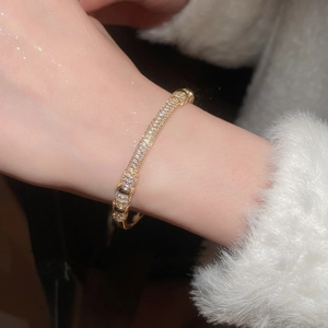 Macro detail of gold plated bracelet featuring shimmering cubic zirconia inlays