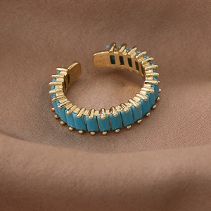 Close-up of golden adjustable ring with blue rectangle zircon on brown silk background