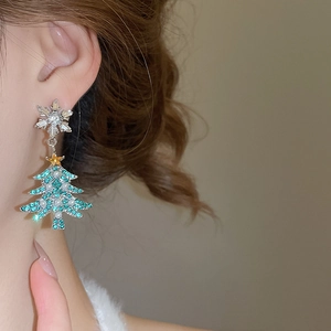 Close-up of snowflake and rhinestone Christmas tree earring with pearl tassels on model
