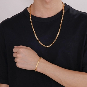 Close-up of golden anchor link chain necklace and bracelet set on a black t-shirt