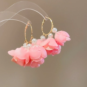 Detailed macro view of pink fabric flower petals and white pearls on gold earrings