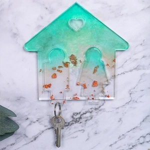 Dettaglio del portachiavi in resina a forma di casa con foglie d'oro e sfumatura verde