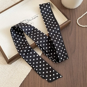 Vista dettagliata di un foulard in seta vintage a pois neri e bianchi in un vassoio di legno