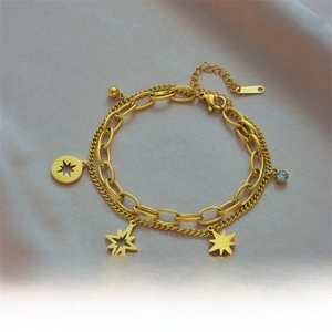 Detail of double-layer gold chain bracelet with star charms and blue gemstone inlay