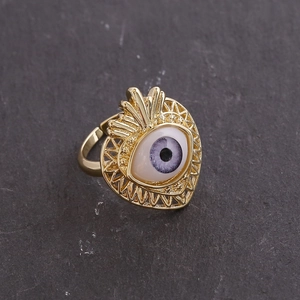 Top-down view of an 18K gold evil eye open ring on a dark stone background