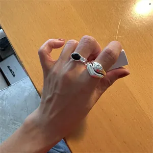 Detail of silver rings set with oval black onyx and fluid liquid metal texture design
