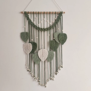 Detailed close-up of handmade sage green and beige macrame wall hanging with wooden beads