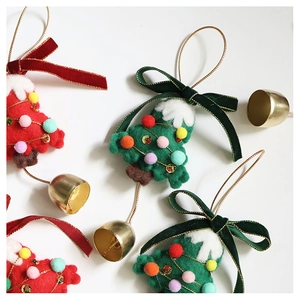 Close-up of wool felt Christmas tree ornaments with golden bells and velvet ribbons