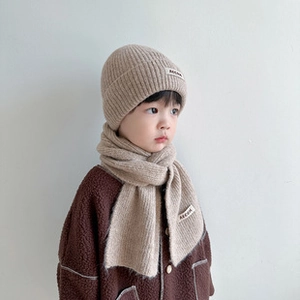 Dettaglio del set cappello e sciarpa in maglia color avena per bambini piccoli