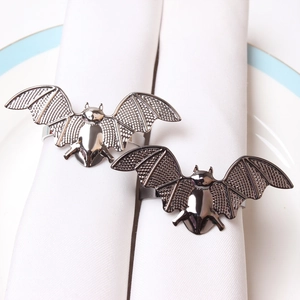 Detailed view of metal bat napkin rings on white fabric with intricate textures