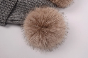 Vue macro détaillée du pompon en fausse fourrure marron clair sur bonnet en maille grise