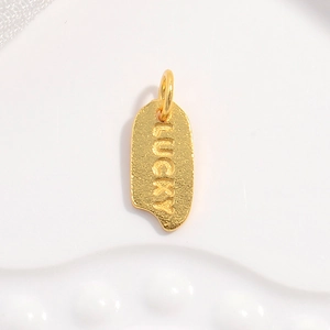 Close-up of golden lucky pendant with embossed letters on textured background