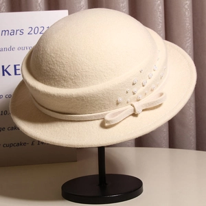 Detail of cream wool fedora featuring a delicate bow and scattered pearl embellishments