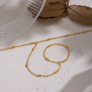 Mise en scène artistique d'un bracelet doré à maillons et perles sur une surface texturée
