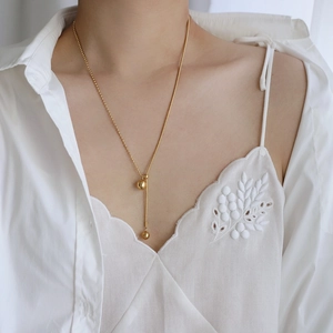 Detail of 18K gold-plated titanium necklace with double bead pendants and snake chain texture
