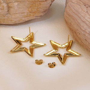 Macro shot of gold hollow star stud earrings with butterfly backs on a textured surface