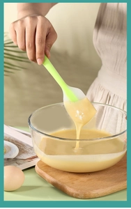 Action shot of neon green silicone spatula mixing batter in a clear glass bowl