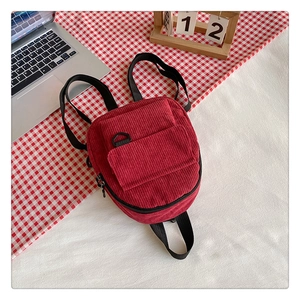 Detail view of red corduroy backpack texture with front zipper pocket and D-ring