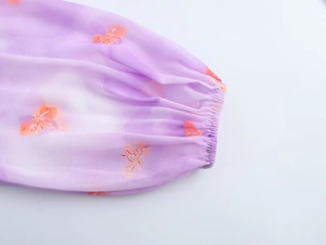 Detail of purple chiffon blouse cuff with orange butterfly print and elastic design