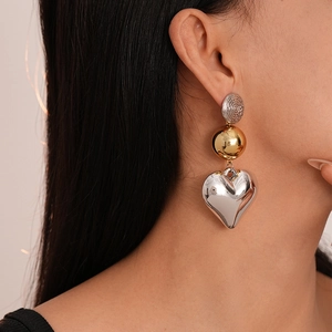 Close-up of geometric heart earrings with metallic finish worn by a fashion model