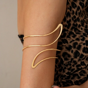Detail of a minimalist gold leaf line upper arm cuff worn on a model arm with leopard print