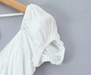 Close-up of ruched puff sleeves on a white backless dress with a lightweight textured fabric