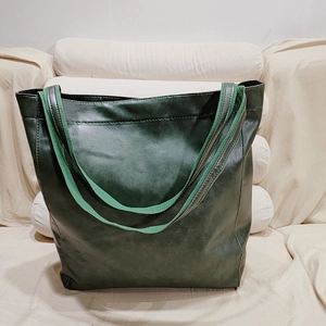 Gros plan sur un grand sac cabas vert foncé avec des anses contrastées