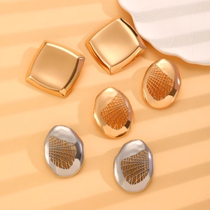 Dettaglio di orecchini color oro e argento con trama lavica e maglia geometrica
