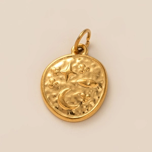Makroaufnahme des goldfarbenen Anhängers mit Relief von Stern, Sichelmond und Augenmotiv