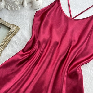 Elegant wine red satin slip dress with V-neck and cross straps on white fabric background