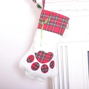 Christmas cat paw stocking with red plaid and green bow hanging on white fireplace