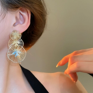 Détail de boucles d'oreilles dorées à couches avec découpures radiales et texture métal