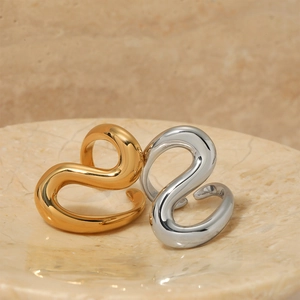 Elegant gold and silver geometric S-curve stainless steel open rings on marble tray
