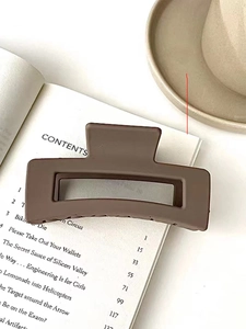 Close-up of a matte brown square hair claw clip placed on an aesthetic open book